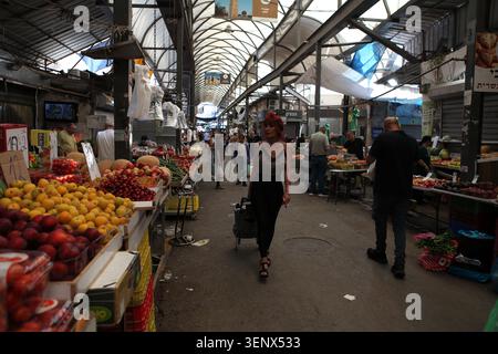 Marché ouvert Ramla, femme avec un panier et d'autres marchent entre les stands du marché avec des fruits comme des abricots, des prunes, des raisins, des melons, des légumes, etc Banque D'Images