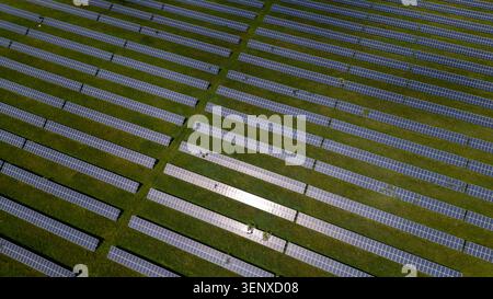 Prise de vue aérienne d'une vaste ferme de panneaux solaires avec des panneaux photovoltaïques soigneusement disposés sur un champ herbeux à Knottingley, Royaume-Uni. Banque D'Images