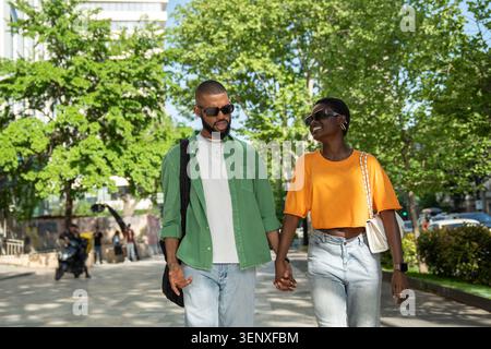 Joyeux couple d'amour afro-américain marchant tenir la main dans la rue de la ville Guy fait rire la petite amie. Banque D'Images