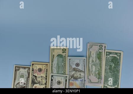 Les piles de billets en dollars américains reposent sur une surface bleue douce. Les factures semblent fraîches et soigneusement groupées. Aucune personne n'est visible, donc pas d'émotions à décrire. T Banque D'Images