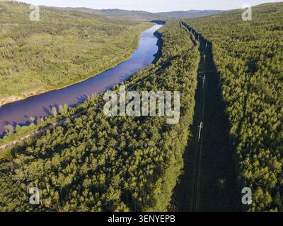 Cette vue sereine met en valeur la beauté naturelle étonnante de Vladivostok, en Russie. Une rivière sinueuse coule à travers une riche forêt verte, avec des lignes électriques tra Banque D'Images