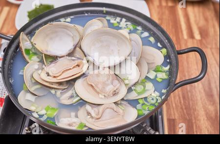 Les plats coréens traditionnels comprennent de grands bivalves frais bouillis dans un bouillon clair associé à du riz blanc cuit à la vapeur et divers accompagnements comme du kimchi épicé Banque D'Images