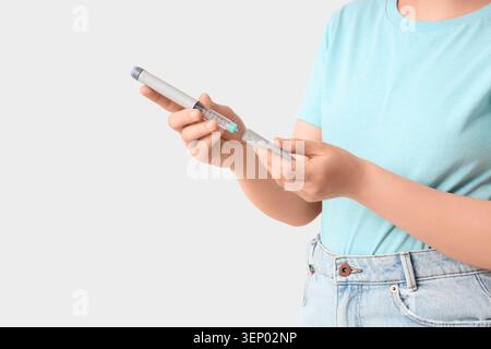 Mains de femmes tenant le stylo d'insuline pour la gestion du diabète, le traitement médical et le concept de soins de santé sur fond blanc Banque D'Images