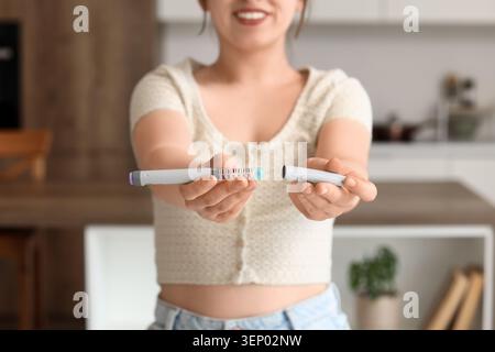 Jeune femme tenant un stylo à insuline pour le traitement médical de gestion du diabète et les soins de santé gros plan des mains avec un dispositif de médicament Banque D'Images