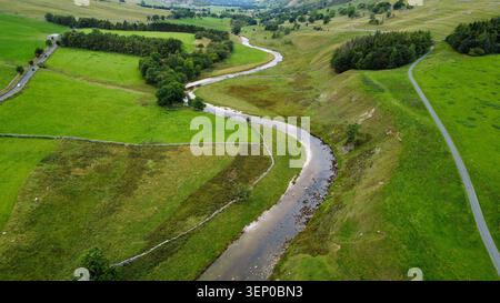 Vue aérienne de la rivière Wharfe serpentant à travers des pâturages verdoyants à côté d'une route étroite à Wharfedale Banque D'Images
