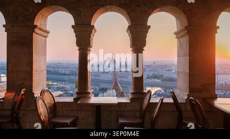Budapest, Hongrie offre une vue imprenable sur le coucher du soleil depuis le Bastion des pêcheurs. Le majestueux bâtiment du Parlement se dresse fièrement contre un ciel vibrant, ce qui en fait un endroit idéal pour se détendre. Banque D'Images