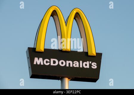 Panneau jaune et noir avec le logo McDonalds sur un ciel bleu Banque D'Images
