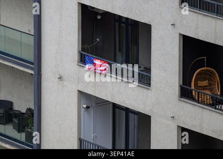 Balcons d'immeuble d'appartements avec un petit drapeau américain accroché à une balustrade dans un cadre résidentiel urbain moderne. Banque D'Images