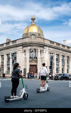 Deux personnes conduisent des scooters électriques partagés à travers une intersection d'asphalte dans le quartier historique de Georgetown à Washington, DC, USA., image verticale. Banque D'Images