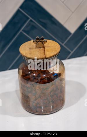 Photo verticale d'un pot en verre rempli de friandises pour chiens. Concept de soin moderne et propre pour animaux de compagnie, stockage des collations pour animaux de compagnie, friandises de récompense saine et esthétique minimale Banque D'Images