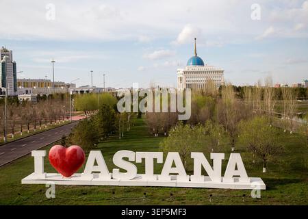 Astana, Kazakhstan – 28 avril 2017 : le panneau « J’aime Astana » est au premier plan avec le palais présidentiel Ak Orda visible en arrière-plan. Banque D'Images