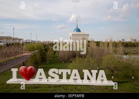 Astana, Kazakhstan – 28 avril 2017 : le panneau « J’aime Astana » est au premier plan avec le palais présidentiel Ak Orda visible en arrière-plan. Banque D'Images