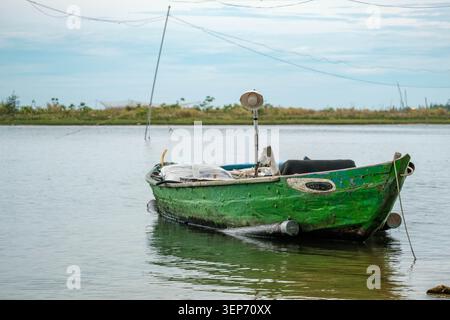 Petit bateau de pêche en bois vert ancré dans l'eau calme Banque D'Images