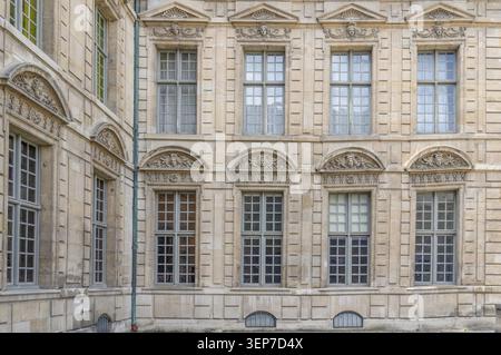 Disposition symétrique grandes fenêtres en treillis et fronton en relief orné sur la façade historique en grès de l'Hôtel de Sully comme symbole de classi Banque D'Images