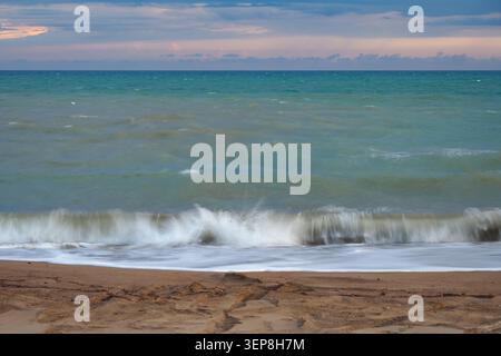 Vagues se brisant sur la plage de sable fin d'après-midi Banque D'Images