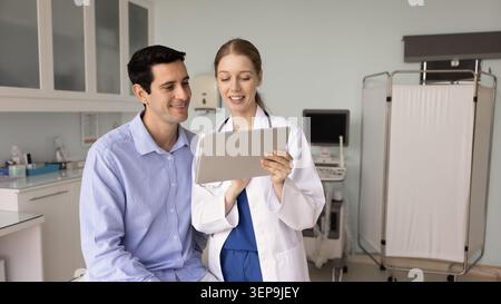 Médecin féminin montrant les résultats de test sur tablette numérique au patient Banque D'Images