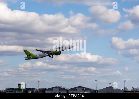 Avion commercial s'élevant abruptement dans un ciel bleu vif rempli de nuages blancs gonflés, parfait pour les concepts de voyage et de tourisme. Banque D'Images