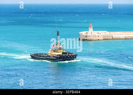 Valletta, Malte – 16 mai 2025 : remorqueur Pawlina naviguant près de l'entrée du port historique et du phare de la Valette, Malte, entouré de turquoise lumineux Banque D'Images