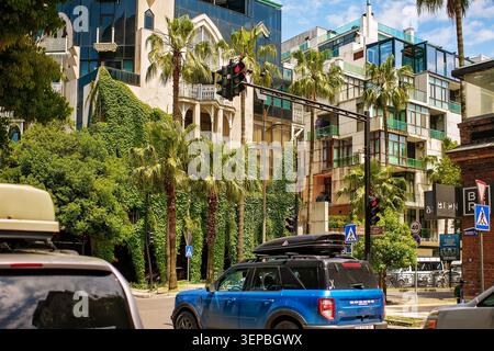 Batumi, Géorgie - 09 juin 2026 : paysage urbain à une intersection avec des voitures stationnaires à un feu rouge, sur fond d'architecture unique Banque D'Images