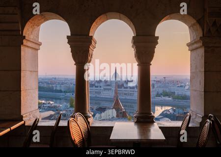 Budapest, Hongrie offre une vue imprenable sur le bâtiment du Parlement hongrois alors que la lumière du soleil s'estompe. Profitez d'un moment paisible dans un charmant café tout en vous imprégnant de cette belle scène au crépuscule. Banque D'Images