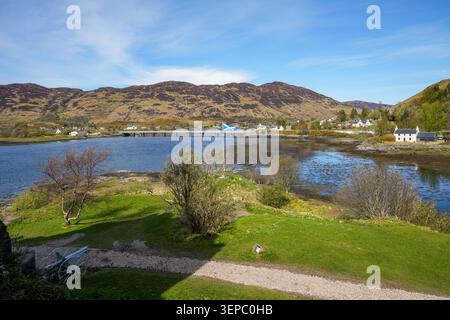 Vue sur le Loch Duich vers le village de Dornie en Écosse, avec le drapeau écossais (Saltire) au premier plan. Les longues montagnes panoramiques en arrière-plan font partie des Kintail Highlands. Banque D'Images