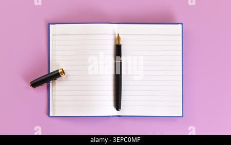 Vue de dessus - stylo noir à encre fontaine avec pointe dorée, bouchon ouvert, tampon de papier blanc vide sur le panneau de lilas sous Banque D'Images