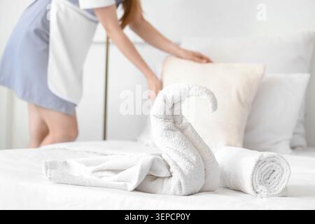 Femme de chambre faisant lit dans la chambre d'hôtel, se concentrer sur les serviettes Banque D'Images