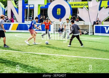 Un groupe de jeunes hommes divers, y compris des joueurs noirs, du moyen-Orient et blancs, participent à un tournoi interactif de mini-football à Nathan Phillips Square. Capturés en pleine action dribbles et en passant un ballon de soccer sur un terrain escamotable, ils jouent contre l'emblématique hôtel de ville de Toronto en toile de fond. Entourée d'une image de marque dynamique, cette scène animée met en valeur l'engagement intense des fans et l'esprit communautaire lors des célébrations officielles de la Coupe du monde de la FIFA 2026 à Toronto Banque D'Images