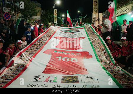 Iran, Iran. 15 juin 2026. Les garçons tiennent une grande bannière montrant un maillot de football iranien et des portraits lors d'un rassemblement organisé par l'État en Iran. le ministère iranien des Affaires étrangères a déclaré que les États-Unis avaient nui aux efforts diplomatiques internationaux pour mettre fin à la guerre après de nouvelles frappes américaines sur des cibles dans le sud de l'Iran, tandis que le président américain Donald Trump a déclaré qu'un accord avec l'Iran pourrait être signé et que le détroit stratégique d'Ormuz serait « ouvert à tous » immédiatement après. L'agence de presse iranienne Fars, citant « une source bien informée proche de l'équipe de négociation iranienne », a rapporté que Téhéran ne l'avait pas encore fait Banque D'Images