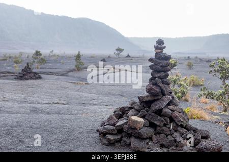 Caire de pierres sur un ancien champ de lave dans le parc national des volcans d’Hawaï sur la Grande Île d’Hawaï, avec le paysage volcanique dramatique de Kīlauea Iki. Banque D'Images