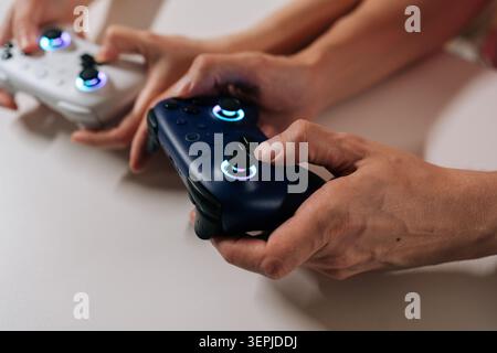 Gros plan recadré d'un jeune couple adulte tenant des manettes de jeu sans fil, jouant à des jeux vidéo ensemble, partageant son temps libre et se divertissant à Banque D'Images