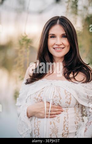 Femme enceinte souriante profitant de la maternité dans la nature Banque D'Images