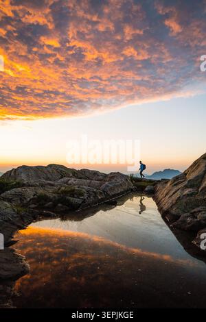 Silhouette de randonneur reflétée dans l'eau au lever du soleil Banque D'Images