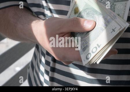 L'homme tient des billets de banque polonais de cent zloty dans sa main. Banque D'Images