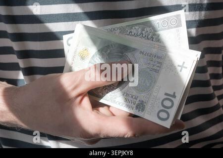 L'homme tient des billets de banque polonais de cent zloty dans sa main. Banque D'Images