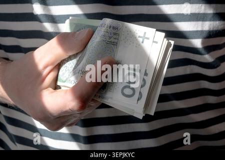 L'homme tient des billets de banque polonais de cent zloty dans sa main. Banque D'Images