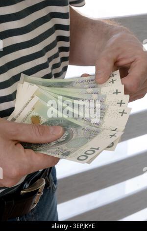 L'homme tient des billets de banque polonais de cent zloty dans sa main. Banque D'Images