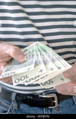 L'homme tient des billets de banque polonais de cent zloty dans sa main. Banque D'Images