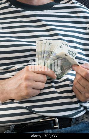 L'homme tient des billets de banque polonais de cent zloty dans sa main. Banque D'Images