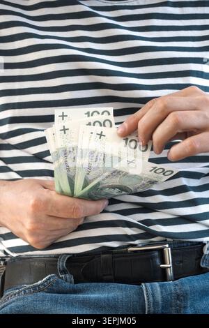 L'homme tient des billets de banque polonais de cent zloty dans sa main. Banque D'Images