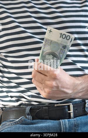 L'homme tient des billets de banque polonais de cent zloty dans sa main. Banque D'Images