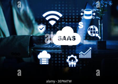 Concept de logiciel SaaS avec des icônes montrant les fonctionnalités et une personne utilisant un ordinateur portable la nuit Banque D'Images