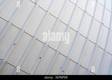 Gros plan détaillé d'une surface de toit métallique avec des feuilles superposées conçues pour la durabilité et la résistance aux intempéries sur un extérieur de bâtiment moderne. Banque D'Images