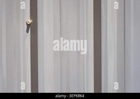 Une image en gros plan d'un mur métallique avec des panneaux verticaux présentant un aspect industriel élégant, avec un boulon sur le côté gauche, idéal pour l'architecture Banque D'Images