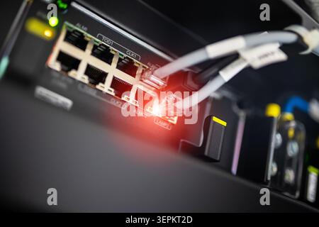 Vue rapprochée d'un commutateur réseau avec plusieurs câbles Ethernet connectés, illustrant l'infrastructure réseau moderne et la technologie de transfert de données. Banque D'Images