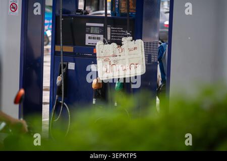 Cette image montre une pompe à carburant dans une station-service avec une affiche manuscrite attachée, indiquant un message dans une langue étrangère. La pompe est dotée d'une digita Banque D'Images