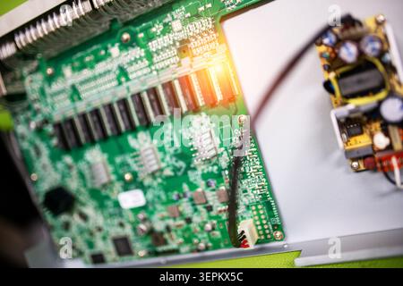 Cette photographie détaillée en gros plan présente une carte de circuit imprimé verte remplie de micropuces, de condensateurs, de résistances et de câblage complexe, Highlig Banque D'Images