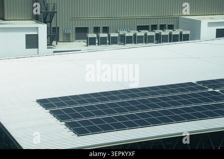Cette image montre un ensemble de panneaux solaires installés sur le toit d'un grand bâtiment industriel, illustrant l'utilisation de la technologie des énergies renouvelables pour produire Banque D'Images