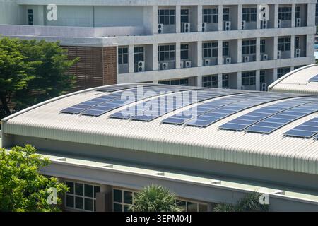 Cette image présente un bâtiment contemporain avec un toit innovant équipé de panneaux solaires, entouré de verdure, illustrant l'architecture moderne Banque D'Images