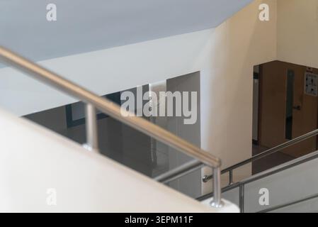 Un intérieur élégant et moderne montrant un couloir avec des escaliers et des garde-corps en métal dans un bâtiment, avec un design épuré, des couleurs neutres et une str contemporaine Banque D'Images